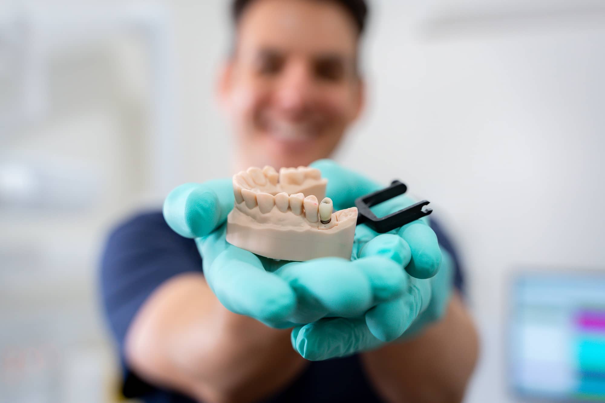 Expert dentist holding clay mouth showing dental implant as option for missing tooth