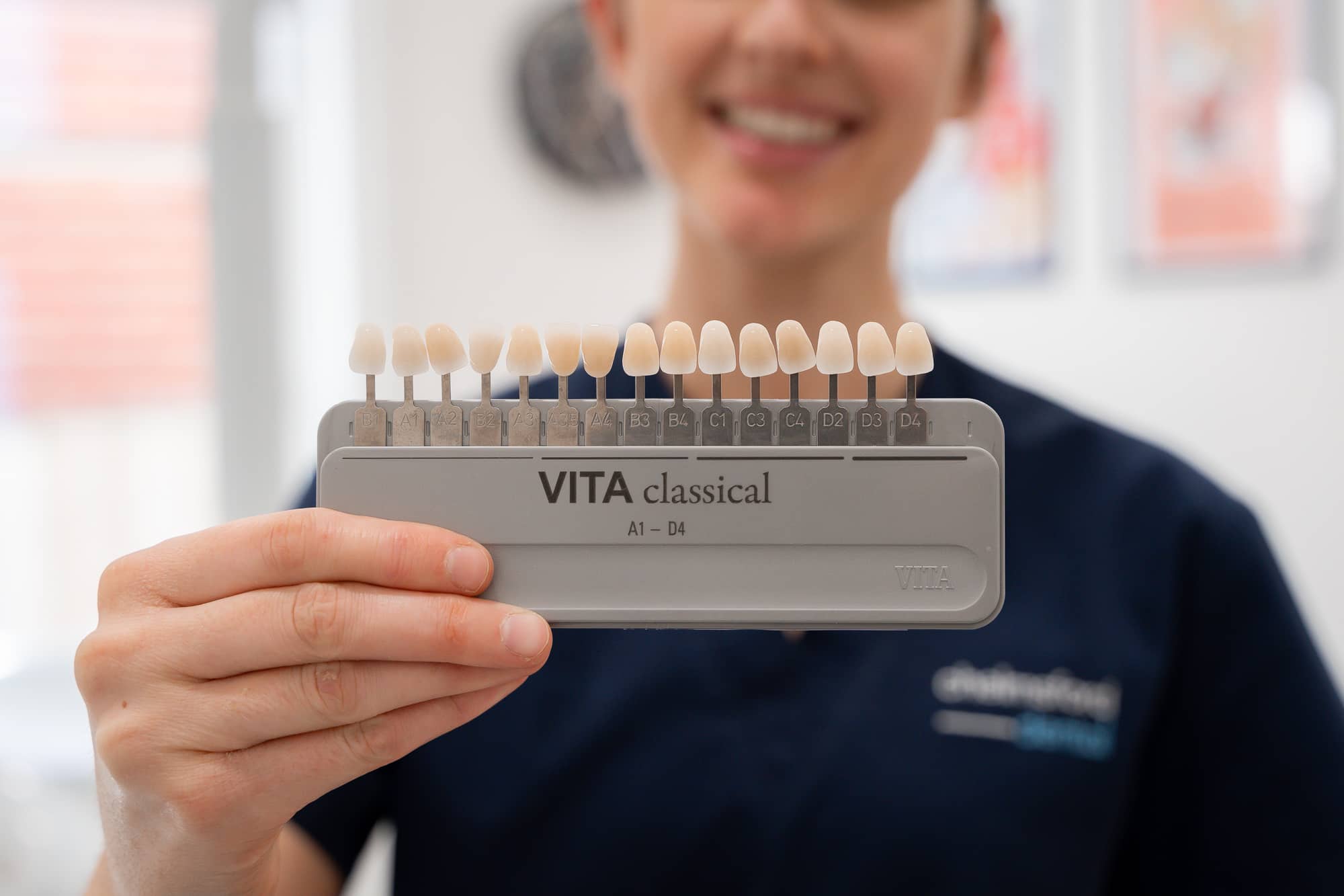 Expert Dentist holding colour match pallet to match veneers to natural teeth