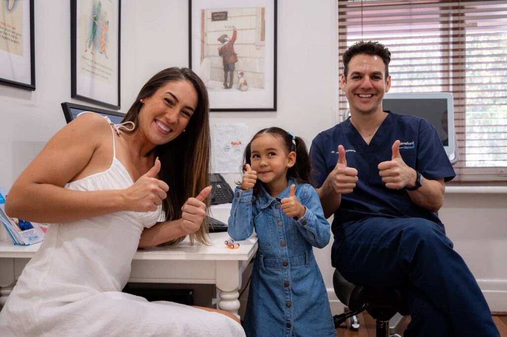 Dr James from Chelmsford Dental with smiling child and adult patient