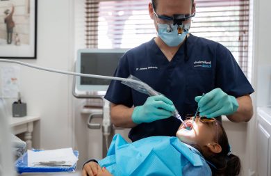 dentist cleaning child teeth at dental clinic