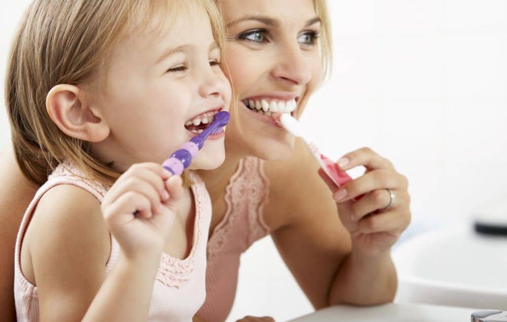 Mother and daughter brushing their teeth.