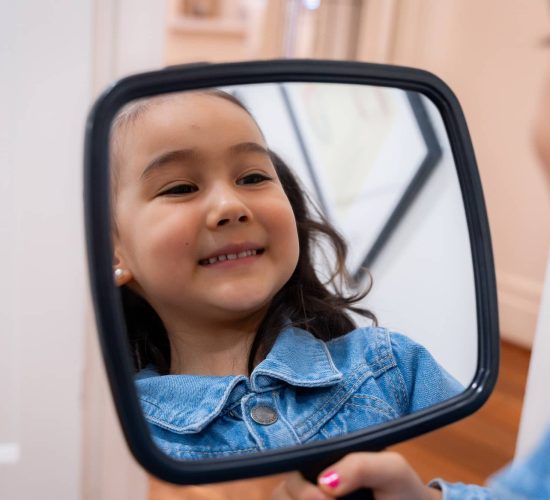 child smiling in mirror checking teeth
