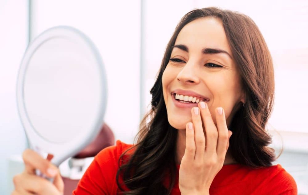 Woman checking her reflection after dental surgery.