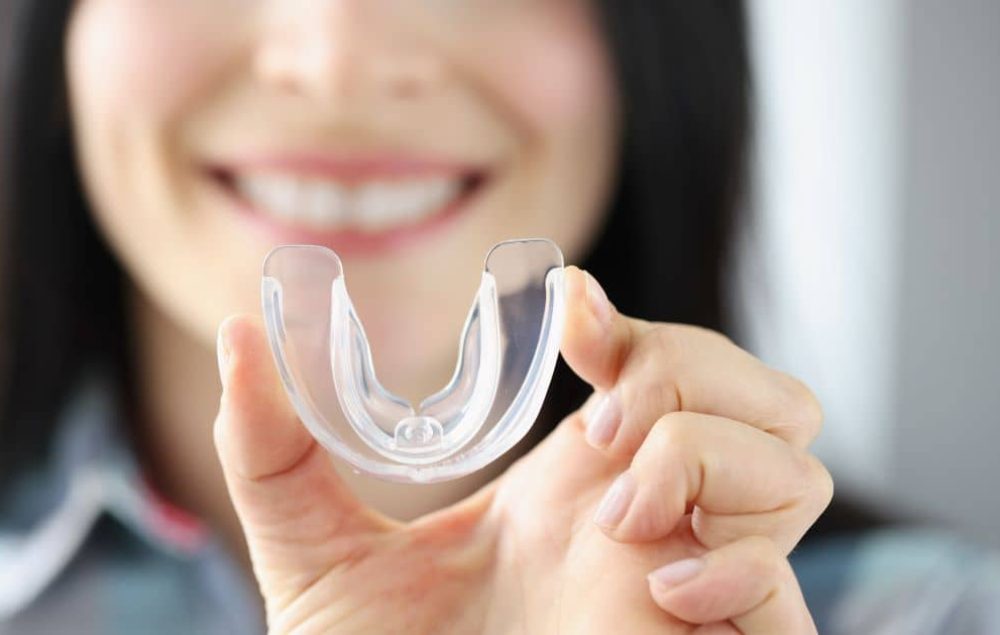 Woman holding mouthguard.